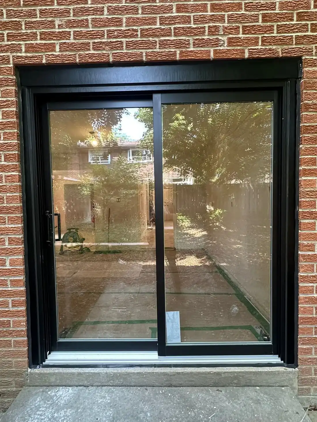 New sliding patio door in brick with a continuous fresh black seal around the full perimeter and across the threshold; straight on, evenly lit and clean top to bottom.