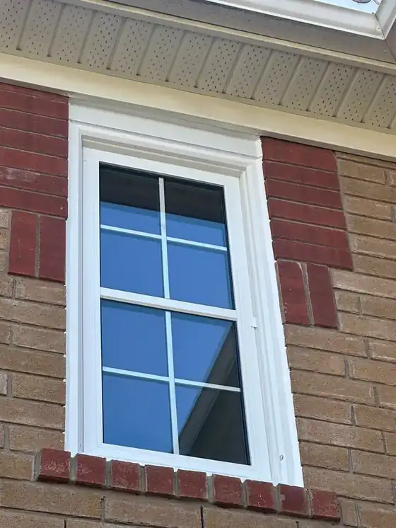 White-trimmed window on red and tan brick with the perimeter bead reading crisply against the masonry; the sharpest frame of this three-shot set.